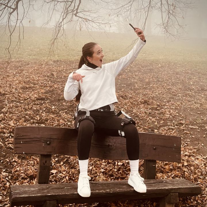 A young girl wearing a Hypershell exoskeleton taking a selfie on a park bench near Normafa in Budapest, Hungary