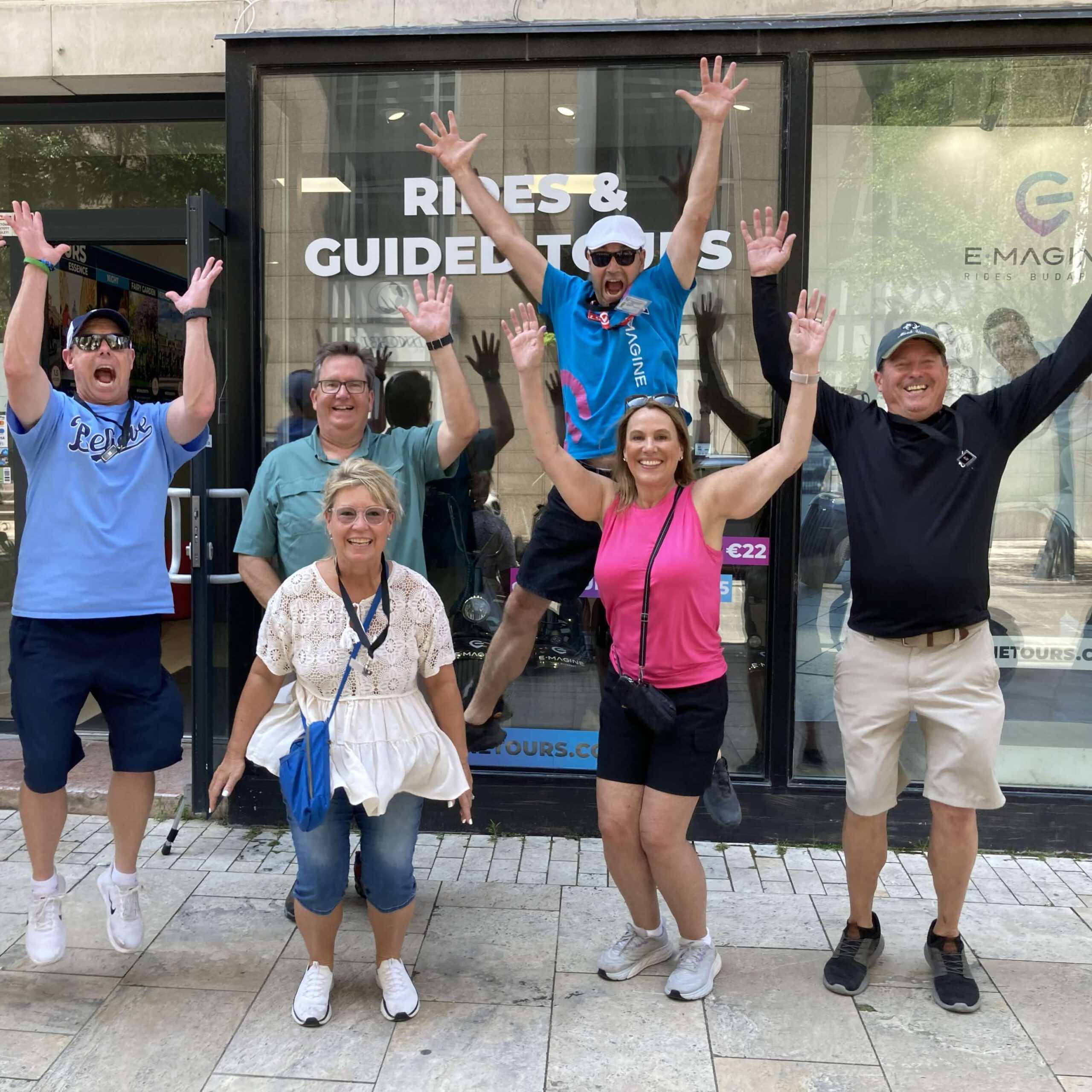 Several people having fun jumping up and waving their hands at the end of a guided e-scooter tour in Budapest, Hungary.