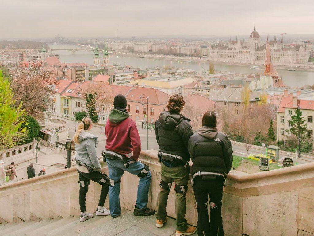 People wearing Hypershell exoskeletons stopping to admire the view of the Parliament from Buda Castle in Budapest, Hungary