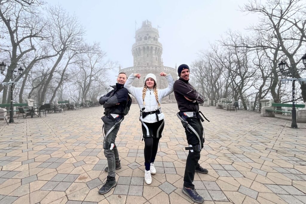 Three people wearing Hypershell exoskeletons posing in front of the iconic Elizabeth lookout in Budapest, Hungary